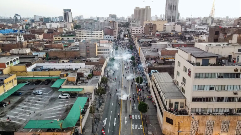 foto aérea en la que se ve una avenida desde aprox 10 pisos de altura, está sin carros, con bombas lacrimógenas y varios policías que se ven bien pequeños.