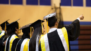 Fotografía en que se ve a cuatro personas de espalda que están con toga y birretes de graduación. Están viendo hacia arriba, al horizonte.