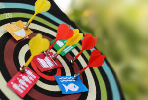 Primer plano de un tablero de dardos coloridos. un grupo de dardos de imanes (sin punta) sostienen pequeños papeles con logos de los objetivos de desarrollo sostenible