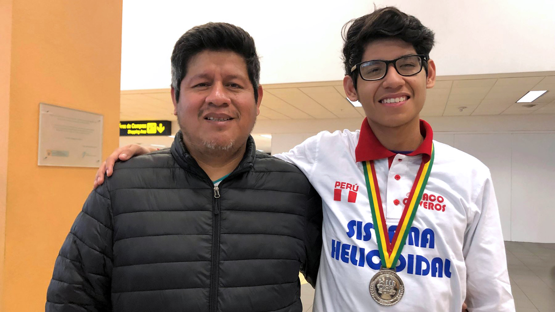 El mismo joven con la medalla abraza a un señor que podría ser su familiar