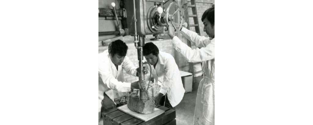 Fotografía en blanco y negro de alumnos de Ingeniería manipulando una máquina en el Laboratorio de Minas.