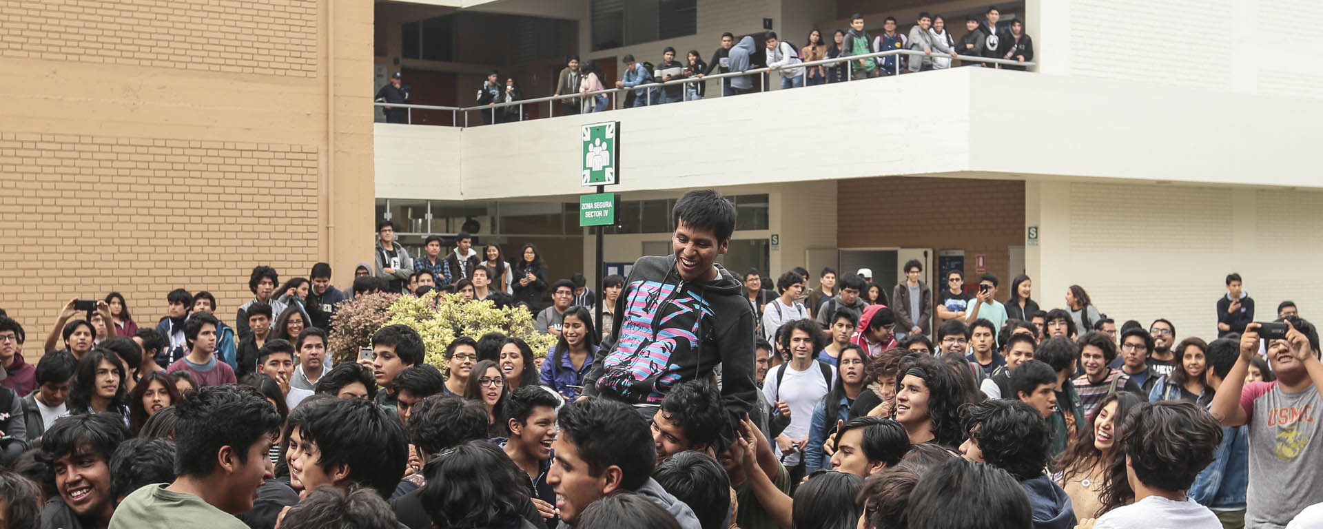 Alumnos en el patio de Estudios Generales Ciencias escuchando y bailando en un concierto de bandas de rock.