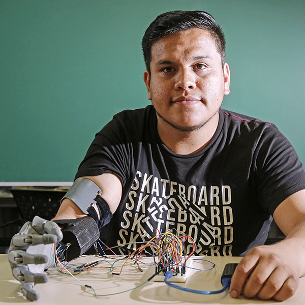 Enzo Romero en un salón de clases usando una prótesis robótica de mano que él diseñó