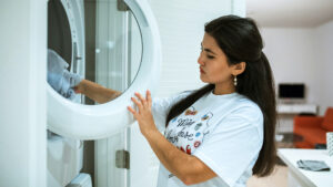 mujer ingresa ropa en lavadora