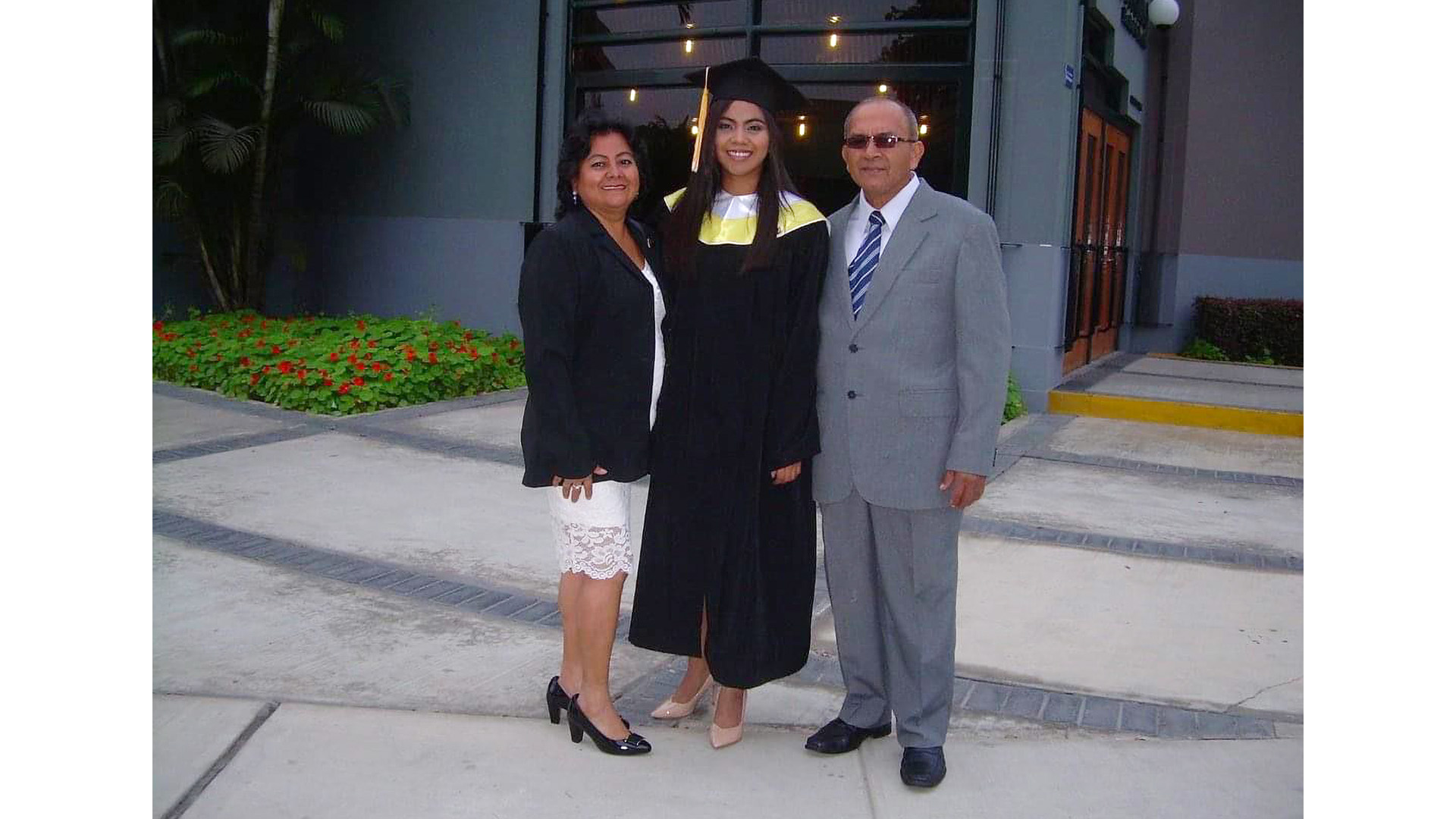 La estudiante con toga y birrete a compañada de sus padres