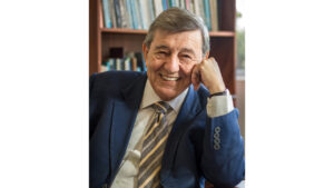 Rafael Roncagliolo posa sonriendo con terno azul y la cabeza apoyada en el brazo