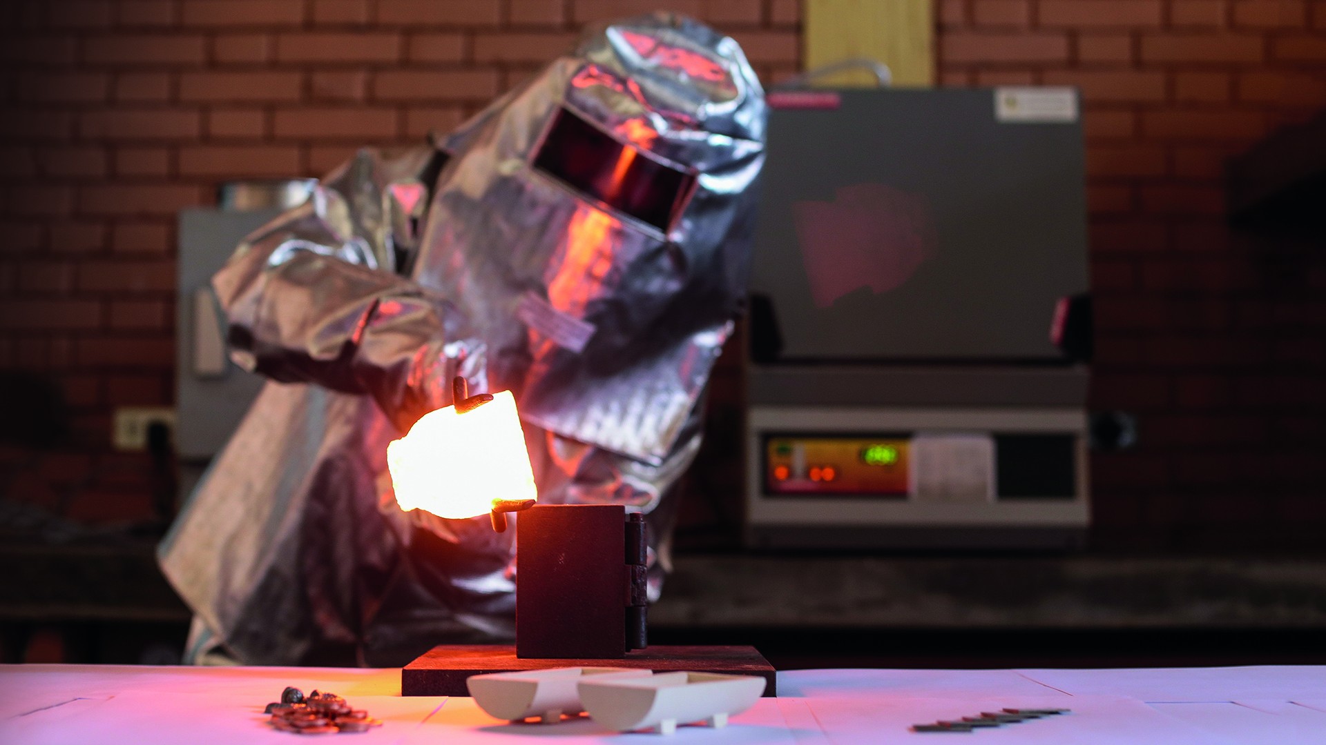 Investigador cubierto con traje metálico de protección haciendo la fundición y extracción del producto a altas temperaturas.