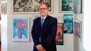 Fotografía del defensor universitario johny zas friz. Está con terno, camisa blanca y corbata azul. ambas manos est´na recogidas a la altura de la cintura. Es un hombre de aproximadamente 55 años, calva incipiente, lentes y sonríe a la cámara. De fondo hay una pared blanca y varios cuadros