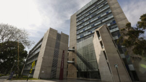 Foto del edificio Mac Gregor. Está en un ángulo contrapicado, desde su explanada se ve hacia arriba su estructura alta de 12 pisos y el cielo de fondo.