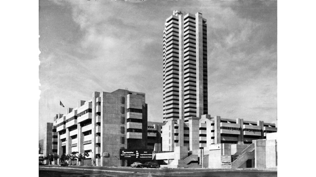 Foto amplia en blanco y negro en la que se ve el centro cívico, un edificio de concreto de más de 20 pisos uqe destaca por su altura.