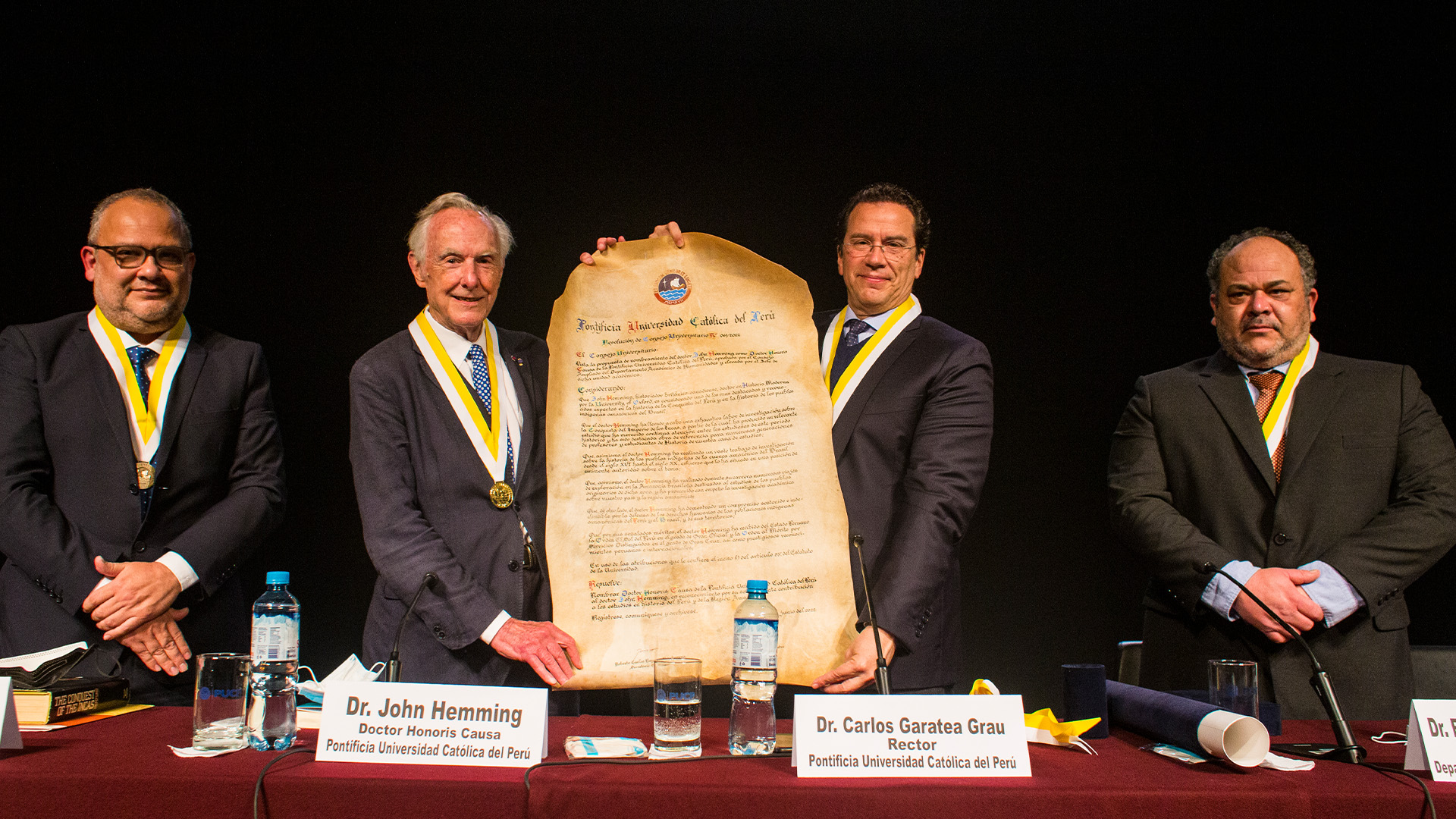 foto de la entrega del doctorado honoris causa a john hemming. está con el rector de la pucp y otros dos señores en terno.