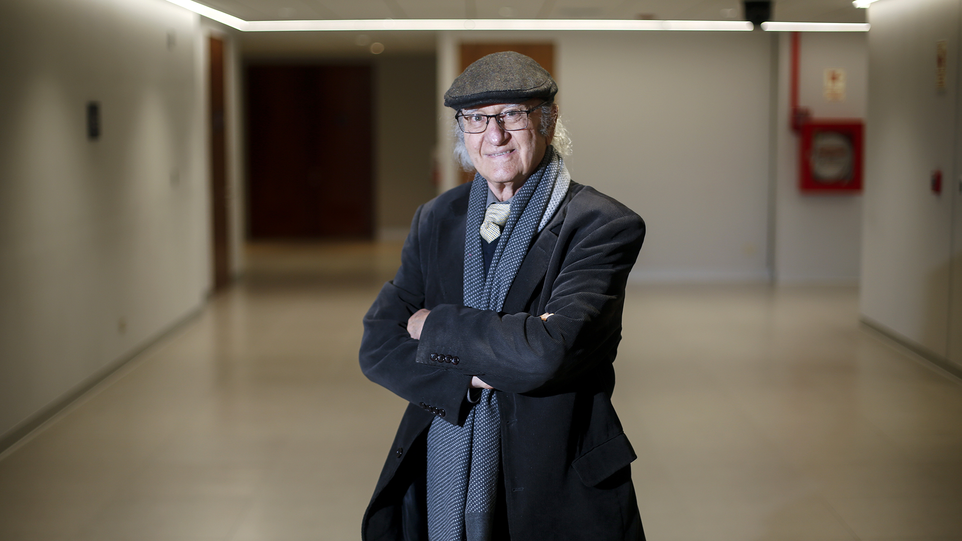 Fotografía de Santiago Graña, profesor emérito de arquitectura PUCP. Es un señor de aprox 70 años con boina que sonríe a la cámara.