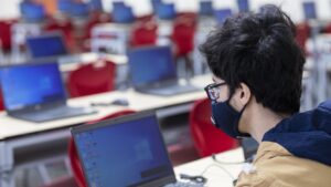 Foto del laboratorio de cómputo de estidos generales ciencias: se ven varias laptops abiertas y un estudiante usando la primera