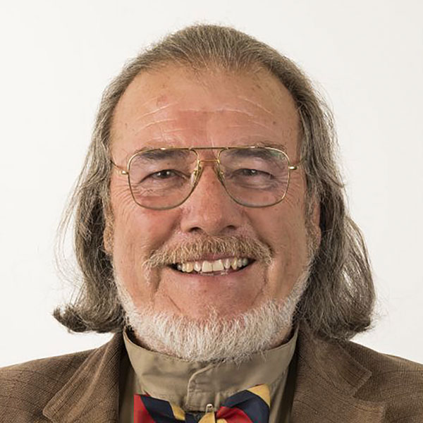 Foto de pedro serrano para puntoedu: es un señor de aprox 60 años, pelo un poco largo castaño claro y barba canosa. Sonríe ligeramente y lleva lentes de marco de metal delgado.