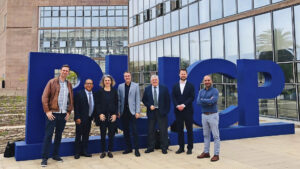 Foto de la visita DAAD a la PUCP: 7 personas delante de letras PUCP azules de 2 metros de altura