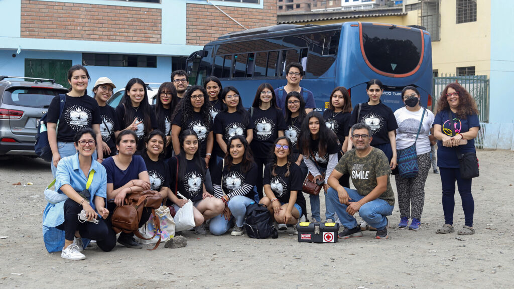 Cocina Poderosa: estudiantes PUCP que participan en este voluntariado (unos 17) están delante de un bus junto a algunas personas de la DARS