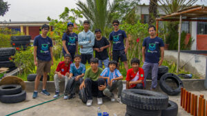 Ganadores del Educactón PUCP 2022 con estudiantes de colegio en san bartolo. están en un jardín trabajando con llantas para reutilizarlas