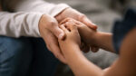 foto para combatir violencia en el entorno escolar: se ve en un plano cercano dos manos de una mujer adulta acogiendo las manos de un niño.