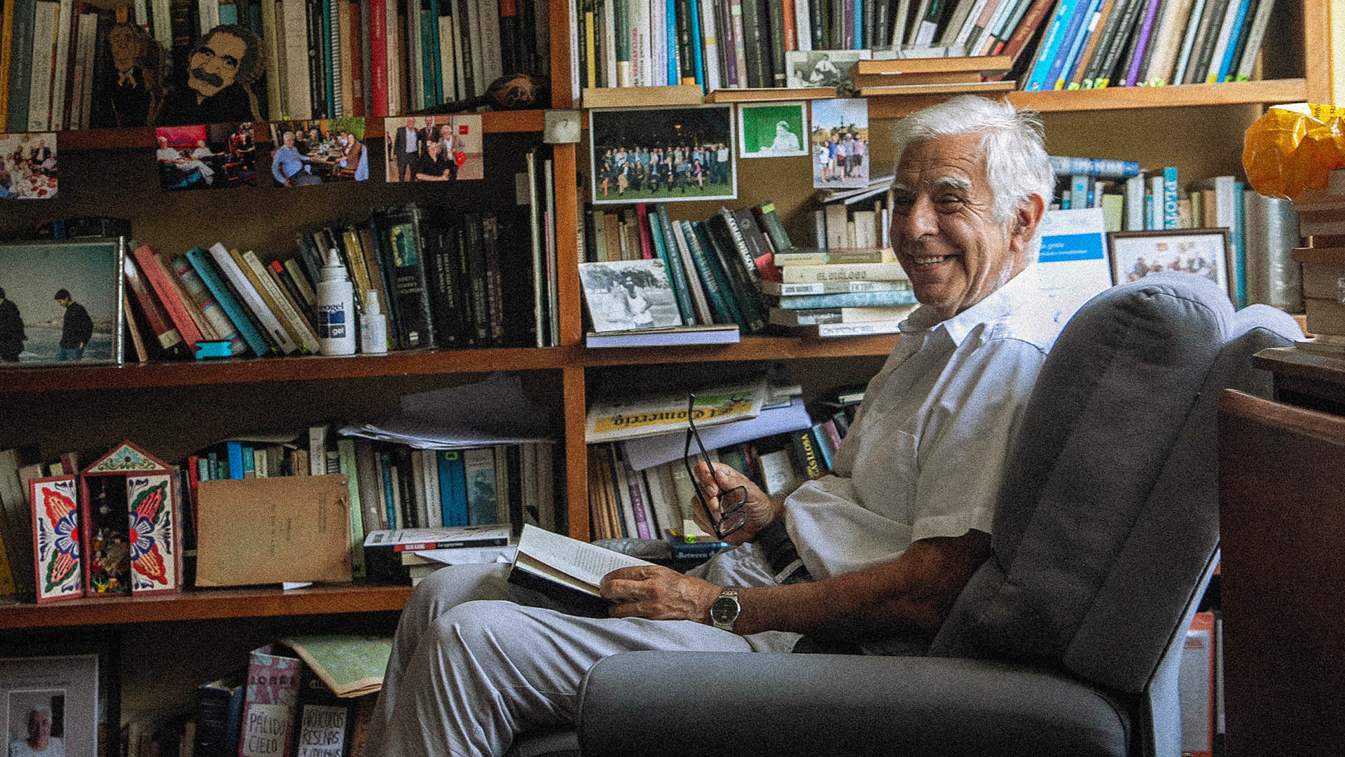 Alonso Cueto sonríe rodeado de libros y fotos