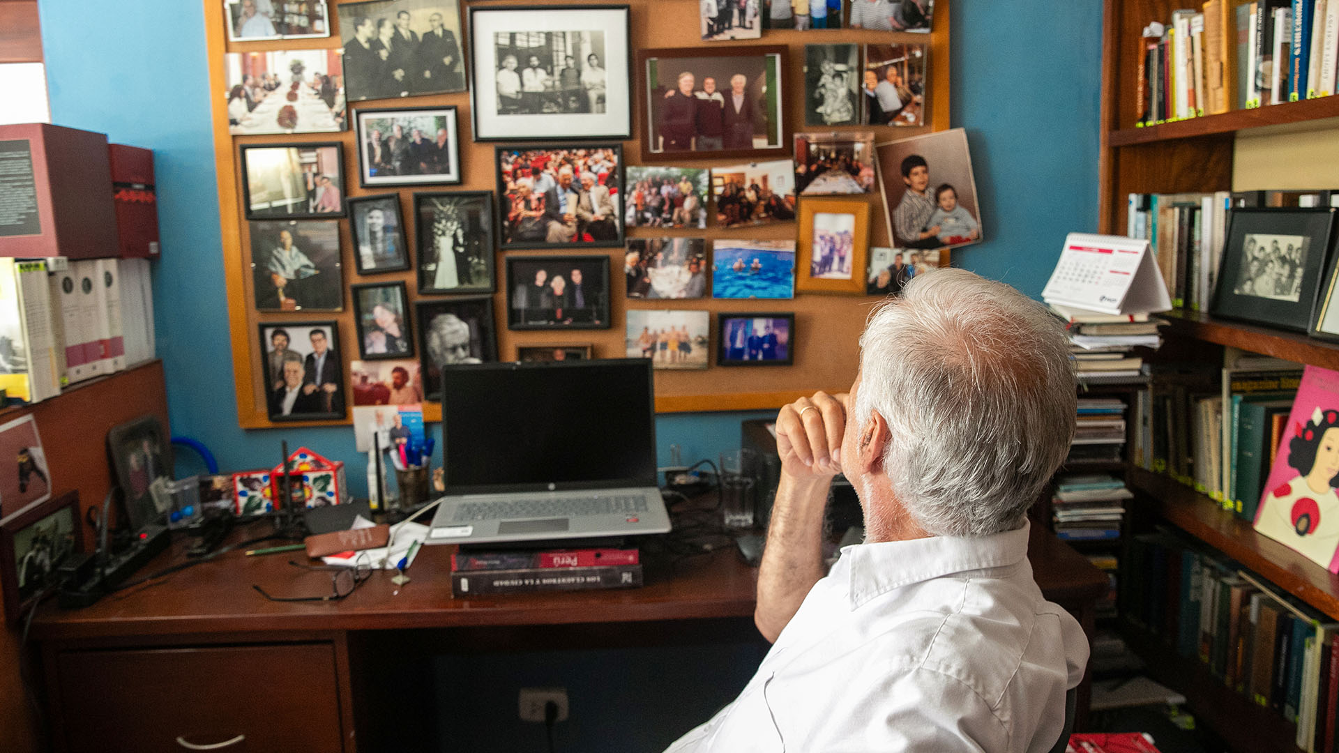 Alonso Cueto sentado frente a su computadora, observando fotos.
