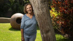 Giovanna Pollarolo parada al lado de un árbol, detrás de ella un jardín.